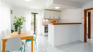 Una cocina moderna con armarios blancos, encimera de madera y horno integrado.