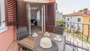 Un balcón con mobiliario de mimbre, una mesa y un sombrero.
