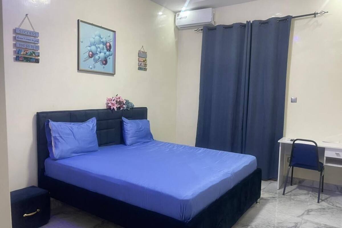A bedroom with a bed, a desk, and a chair.