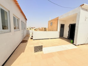 Un immeuble résidentiel doté d’un patio carrelé, d’un petit muret en briques et d’une porte donnant sur un espace intérieur.