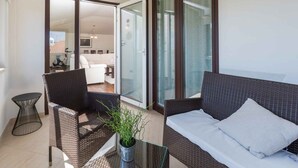 A balcony with wicker furniture, a glass table, and a potted plant. - Holiday apartment with air conditioning (Vrsar)