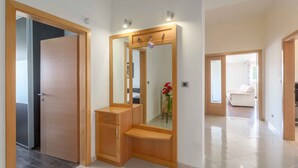 A modern bathroom with a wooden vanity, a large mirror, and a vase with red flowers. - Holiday apartment with air conditioning (Vrsar)