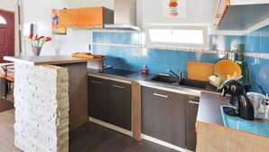Eine kompakte Küche mit integrierter Kücheninsel, dunklen Schränken und einer blau gefliesten Spritzschutzwand.