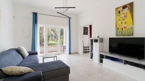 Una sala de estar moderna con un sofá, televisión, obras de arte y vistas a través de un ventanal.