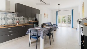 Una cocina moderna con armarios oscuros, un salpicadero con diseño y un comedor con una mesa dispuesta para dos.