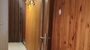 Una puerta de madera con manija metálica, suelo blanco y pared marrón.