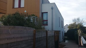 En modern bostadsbyggnad i två våningar med en träfasad och en vit överdel.