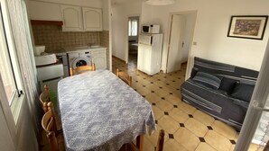 Ein kompakter Wohnbereich mit Essbereich, Küchenzeile und einer Couch.