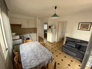 A compact living space with a dining area, kitchenette, and a sofa. - Air-Conditioned Apartment 4/5 People with Parking (Argelès-sur-Mer)