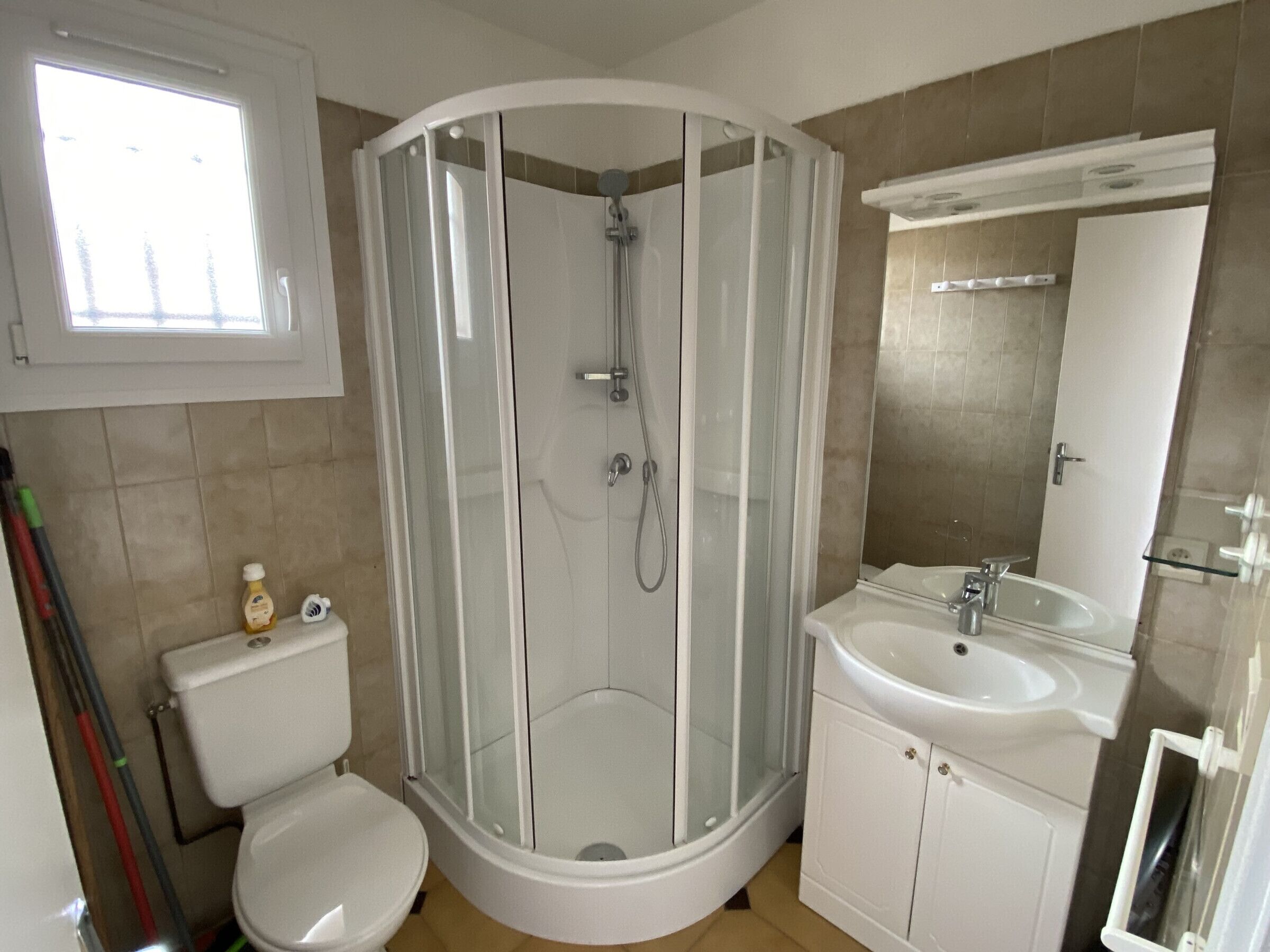 Ein Badezimmer mit Duschkabine, Toilette, Waschbecken und Spiegel.