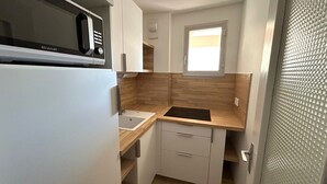 Een kleine keuken met een inbouwmagnetron, een raam en een spoelbak.