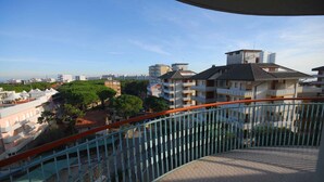 Zona residencial com vários edifícios de apartamentos, varanda curva com guarda-corpo de metal e vista ampla do bairro.