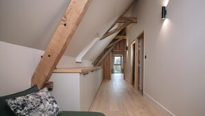A narrow hallway with wooden beams, a green sofa with a patterned pillow, and a wooden counter. - 14th Century Authentic Charm with WiFi and Parking in Contigny (Contigny)