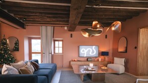 A cozy living room with a blue sofa, a wooden coffee table, and a TV mounted on the wall. - 14th Century Authentic Charm with WiFi and Parking in Contigny (Contigny)