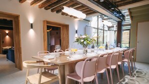 A modern dining area with a long wooden table set for a meal, surrounded by pink chairs. - 14th Century Authentic Charm with WiFi and Parking in Contigny (Contigny)