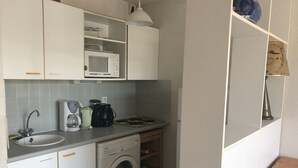 Cocina compacta equipada con lavamanos, microondas, cafetera y lavadora.