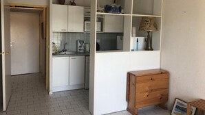 Una cocina compacta con alacenas blancas, un mueble de madera, un lavamanos y una cafetera.