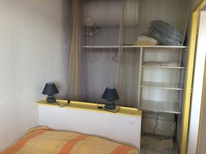 A bedroom with a bed, two bedside lamps, a wardrobe with hanging space, and a window with curtains. - 6-Person Apartment at the Port with Private Parking (Argelès-sur-Mer)