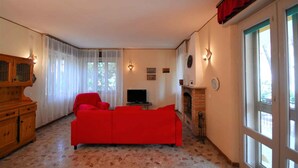 Una sala de estar con un sofá rojo, un televisor, una chimenea y un aparador de madera.