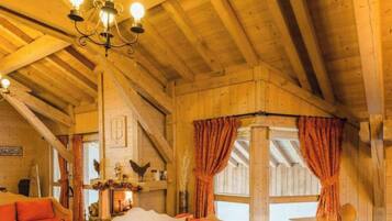A rustic wooden interior with a fireplace, wooden beams, and a chandelier.