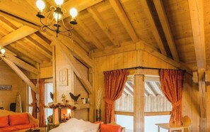 Ein rustikales Holzinterieur mit Kamin, Holzbalken und einer Chandelüster.