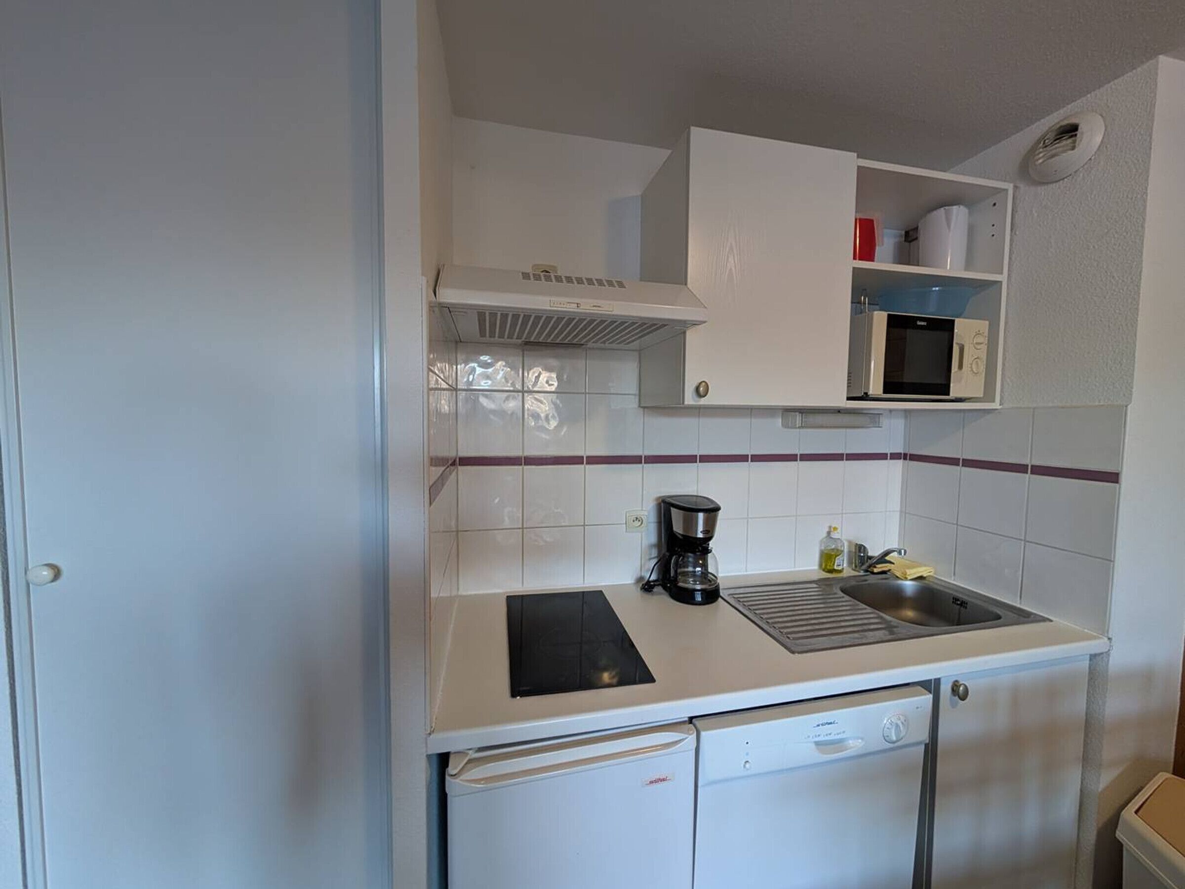 A compact kitchen with a microwave, coffee maker, and a small sink.