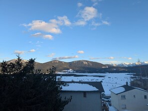 Ein Wohngebiet mit Häusern, verschneiter Landschaft und Bergen im Hintergrund.