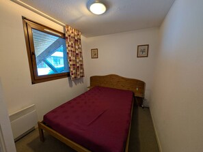Ein kleines Schlafzimmer mit einem Einzelbett, einem Fenster mit Blick und einer Deckenleuchte.