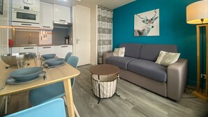 A compact living space with a kitchenette, a dining area, and a seating area with a sofa and a lamp. - Studio for 4 in Tignes, Pets allowed (Tignes)
