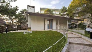 Un edificio moderno con techo plano, una zona exterior cubierta y un césped bien cuidado.