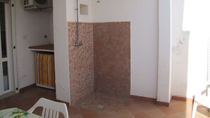 Ein Badezimmer mit Dusche, Ventilator und Fliesenboden.