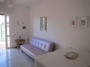 A room with a sofa, a small table, and a framed picture on the wall.