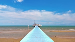 A pier extending into the sea with a building at the end. - Holiday apartment with large corner terrace (Lignano Sabbiadoro)