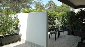 A patio area with a white partition, outdoor seating, and potted plants. - Holiday apartment with large corner terrace (Lignano Sabbiadoro)