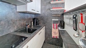Eine moderne Küche mit Gasherd, Kaffeemaschine und hängenden Küchenutensilien.