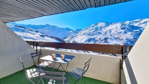 Ein Balkon mit Blick auf schneebedeckte Berge, einem Tisch mit Stühlen und künstlichem Grünbelag.