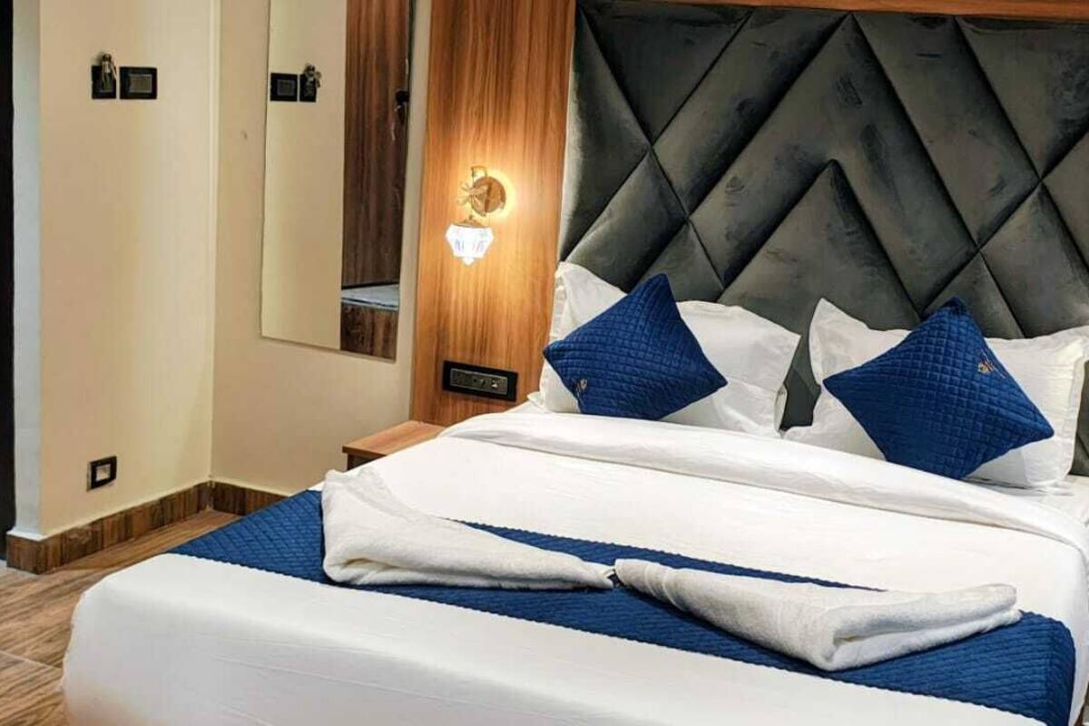 A neatly made bed with a quilted headboard, two bedside tables with lamps, and a mirror on the wall.