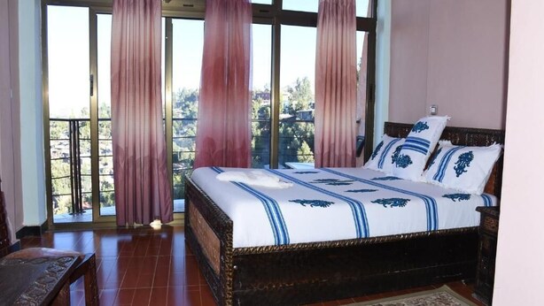 Un dormitorio con una cama grande, cortinas y vistas por una ventana.