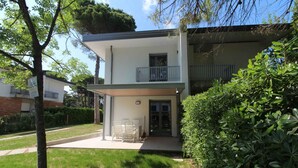 Un edificio a due piani con un portico coperto, un balcone e un prato curato.