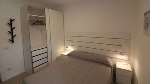 Una camera da letto con un letto, comodini, un armadio e un attaccapanni a parete.