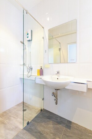 Une salle de bain moderne avec une douche à parois de verre, un lavabo blanc et un miroir au-dessus.