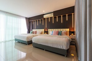 Une chambre d’hôtel moderne avec deux lits, une grande fenêtre avec des rideaux légers, un climatiseur fixé au mur et un design épuré et contemporain.