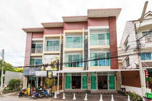 Un hôtel à plusieurs étages, doté d’une façade moderne, d’une entrée couverte et d’une enseigne bien visible pour un restaurant à la thématique rétro.