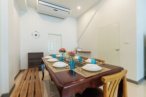 Un coin repas avec une table en bois dressée pour quatre personnes, de la verrerie bleue et une horloge au mur.