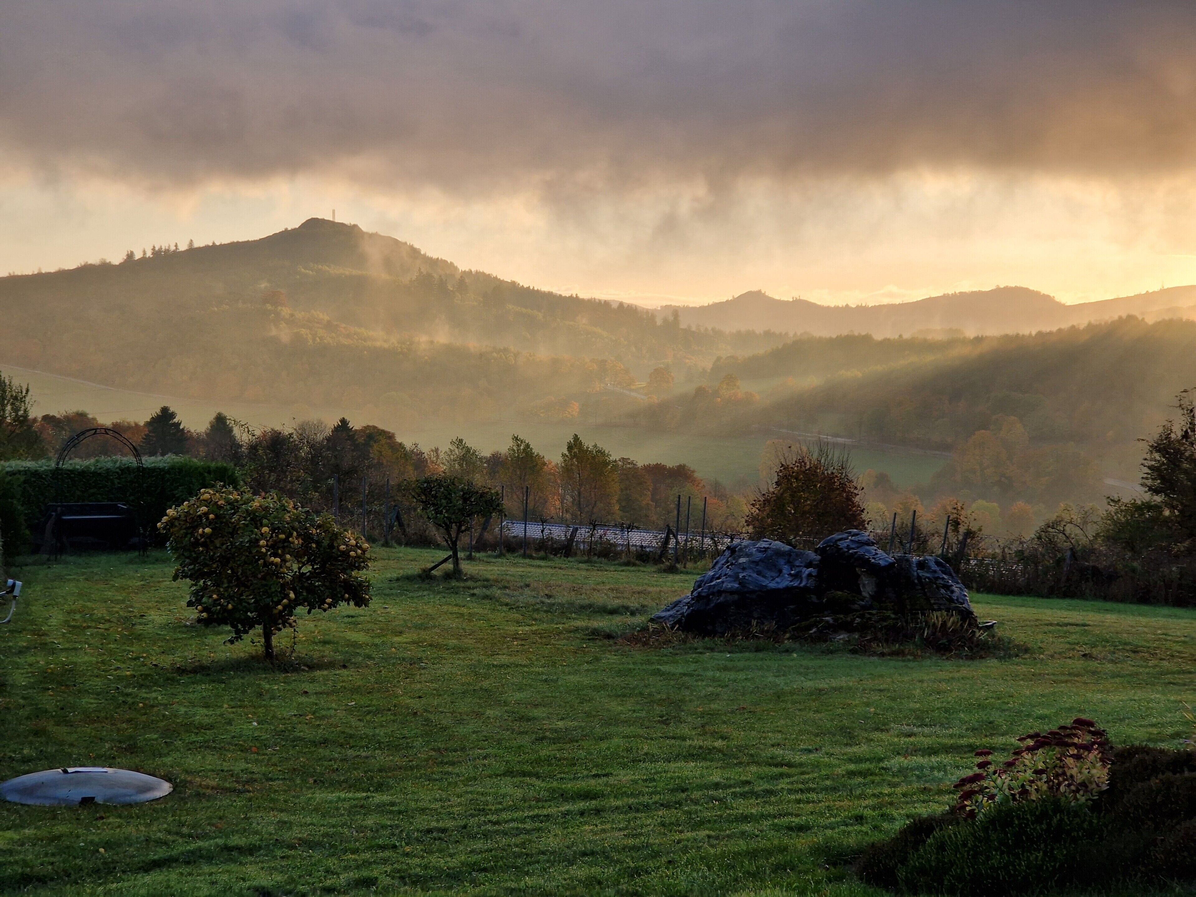 A grassy field with a rock formation and a metal structure.