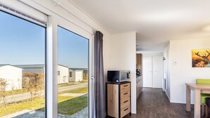 A modern kitchen with a microwave, wooden cabinets, and a view of a residential area. - Tiny Home 'Chalet 91' with Mountain View, Private Terrace, and Wi-Fi (Brilon)