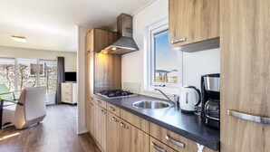 A modern kitchen with wooden cabinets, a stainless steel sink, and a window overlooking a balcony. - Tiny Home 'Chalet 91' with Mountain View, Private Terrace, and Wi-Fi (Brilon)