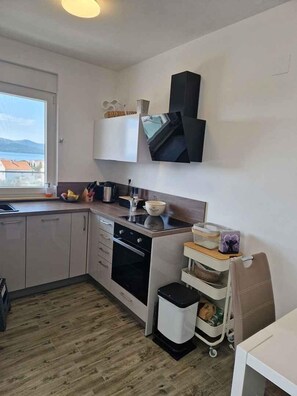Eine kompakte Küche mit Einbauofen, Spüle und Fenster mit Meerblick.