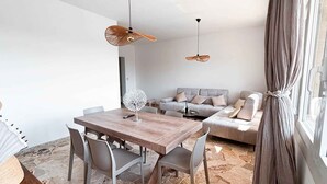 A modern living space with a dining area, a sofa set, and a stone-tiled floor. - Holiday apartment with air conditioning (Jesolo)