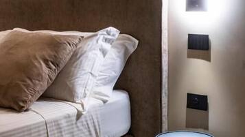 Un dormitorio moderno con una cama, una mesita de noche e iluminación en la pared.